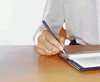 a person sitting at a desk writing in a leger